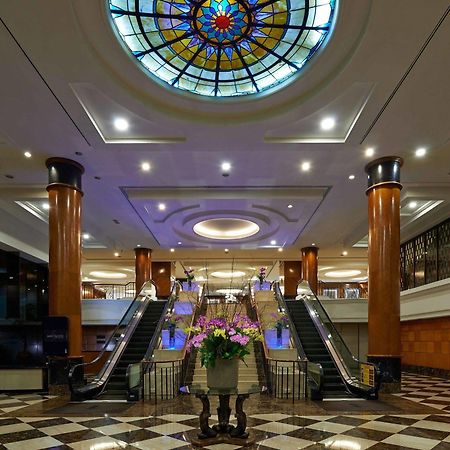 Seri Pacific Hotel Куала-Лумпур Экстерьер фото The photo depicts an elegant hotel lobby featuring a large stained glass ceiling that adds a colorful touch to the space. The lobby has polished marble flooring with a checkerboard pattern. In the center, there is a beautiful arrangement of flowers i