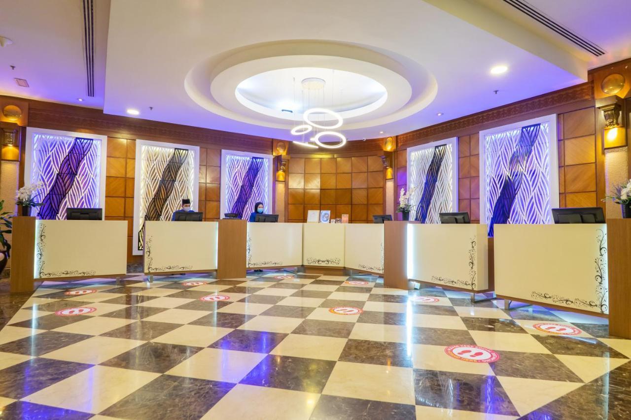 Seri Pacific Hotel Куала-Лумпур Экстерьер фото The photo shows a modern reception area with a stylish design. There are multiple reception desks arranged in a semi-circle, each with a computer setup. The flooring features a black and white checkered pattern, adding elegance to the space. The wall