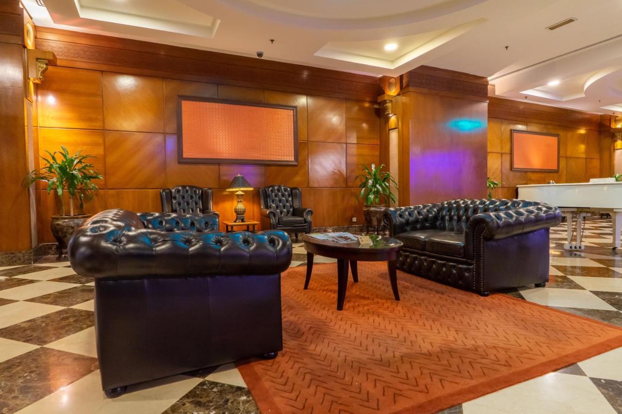 Seri Pacific Hotel Куала-Лумпур Экстерьер фото The photo shows a stylish lounge area featuring leather furniture. There are two black leather sofas with tufted designs and a circular coffee table in the center. The flooring consists of a patterned tile design, and there is a large area rug in an 