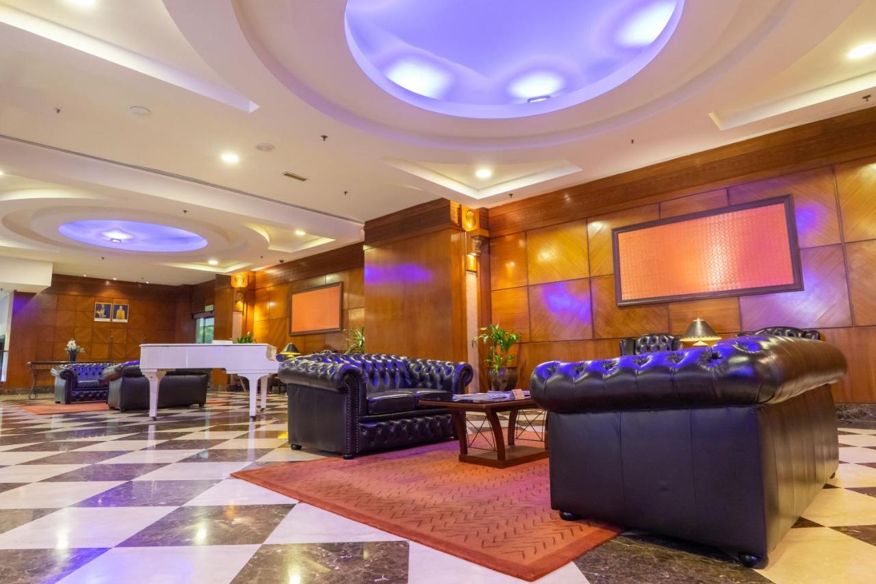 Seri Pacific Hotel Куала-Лумпур Экстерьер фото The photo shows a spacious and elegantly designed lobby area. It features luxurious black leather sofas arranged around a coffee table, creating a welcoming sitting area. The floor has a striking black and white checkered pattern, complemented by war