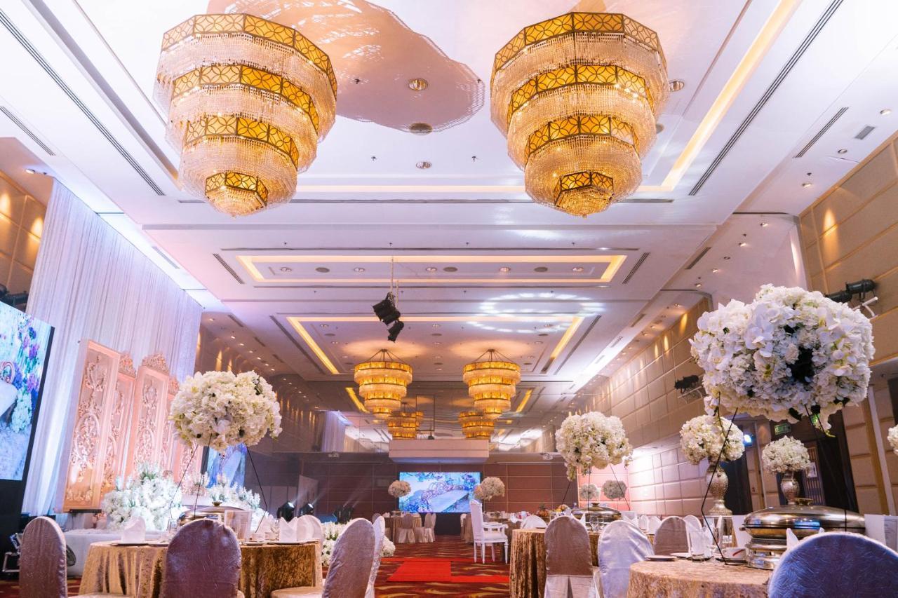 Seri Pacific Hotel Куала-Лумпур Экстерьер фото The photo shows a beautifully decorated banquet hall or event space. There are elegant chandeliers hanging from the ceiling, providing warm lighting. The tables are round and covered with gold tablecloths, and each table is adorned with large floral 