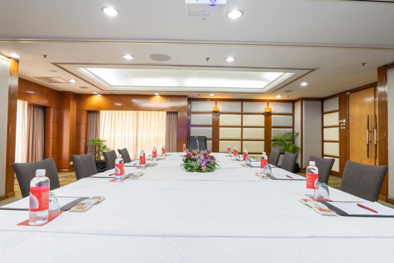 Seri Pacific Hotel Куала-Лумпур Экстерьер фото The photo shows a well-arranged conference room. In the center, there's a large rectangular table covered with a white tablecloth. Surrounding the table are several gray chairs. On the table, there are bottles of water, stationery, and a floral cente