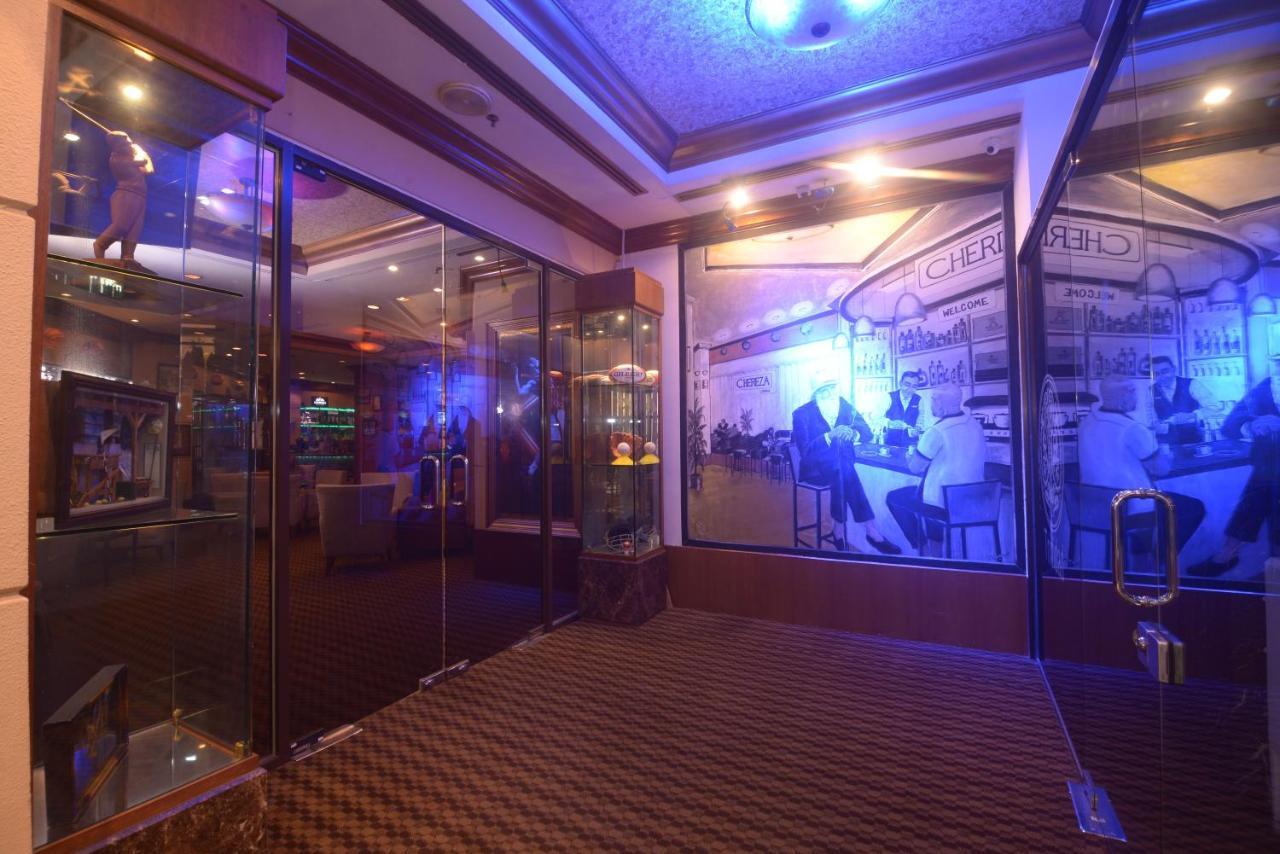Seri Pacific Hotel Куала-Лумпур Экстерьер фото The photo shows an interior space featuring a modern design. There are glass walls and doors that create an open and inviting atmosphere. The walls are adorned with large images that depict scenes of people, possibly from a social or dining setting. 