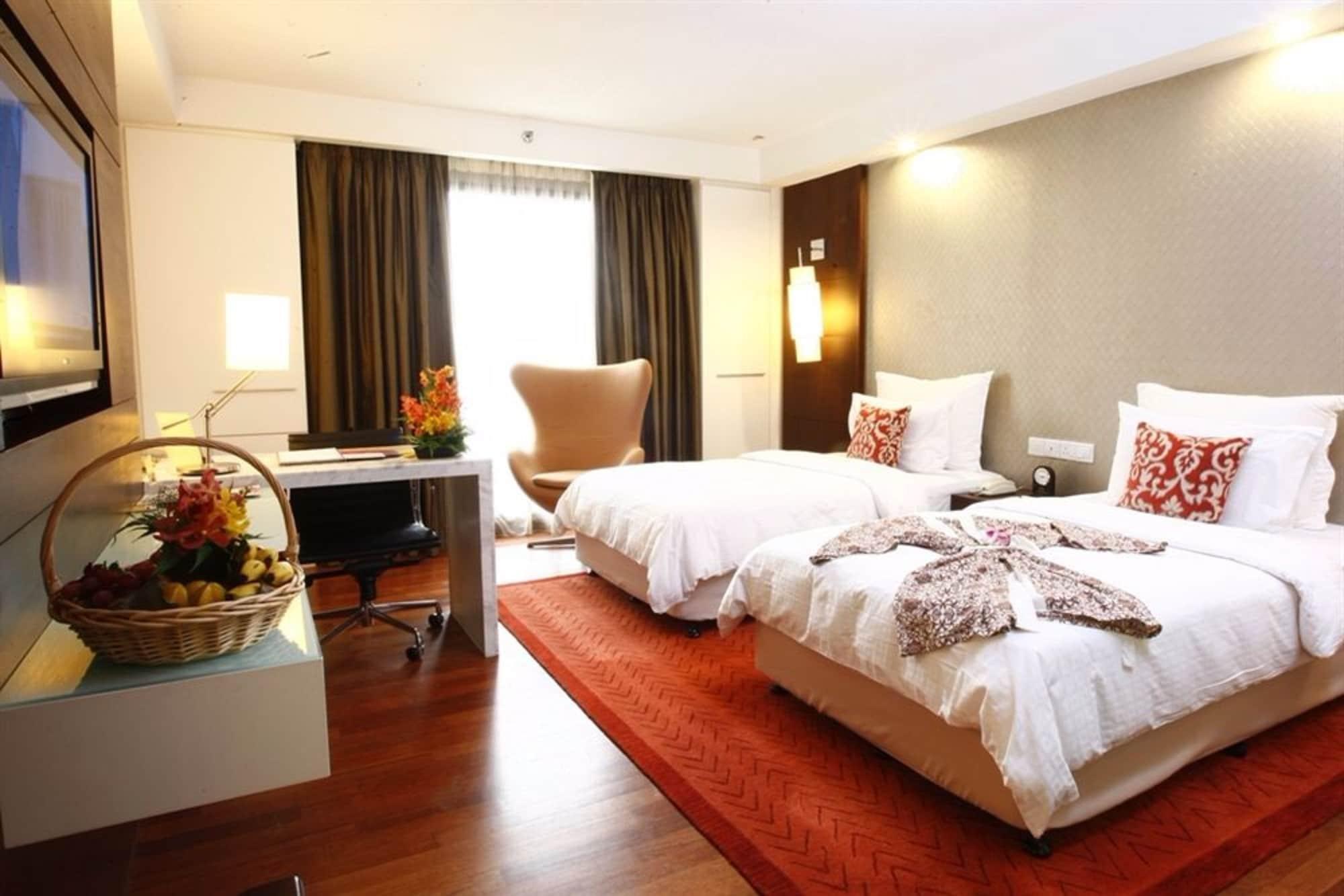 Seri Pacific Hotel Куала-Лумпур Экстерьер фото The photo shows a neatly arranged hotel room featuring two beds: one is a single bed and the other appears to be a larger size. The bed linens are white with decorative throw pillows. A brown area rug lies on the wooden floor, and there is a stylish 