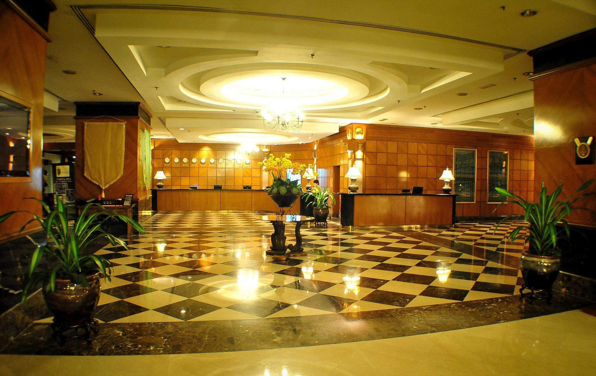 Seri Pacific Hotel Куала-Лумпур Экстерьер фото The photo shows the interior of a hotel lobby. The space features an elegant design with a large, decorative ceiling light in the center. The floor has a checkered pattern made up of black and white tiles, contributing to a sophisticated ambiance. Th
