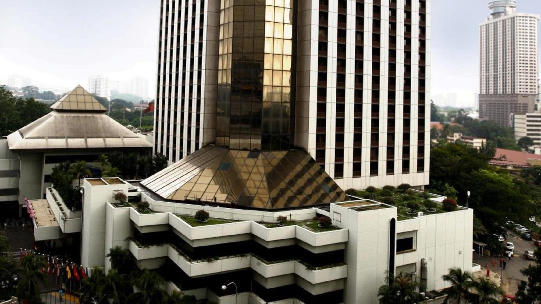 Seri Pacific Hotel Куала-Лумпур Экстерьер фото The photo shows a multi-story building with a modern architectural design. The structure features a prominent glass facade, reflecting the sky and surroundings. The roof has a distinctive angular shape made of gold-toned materials. Surrounding the ba
