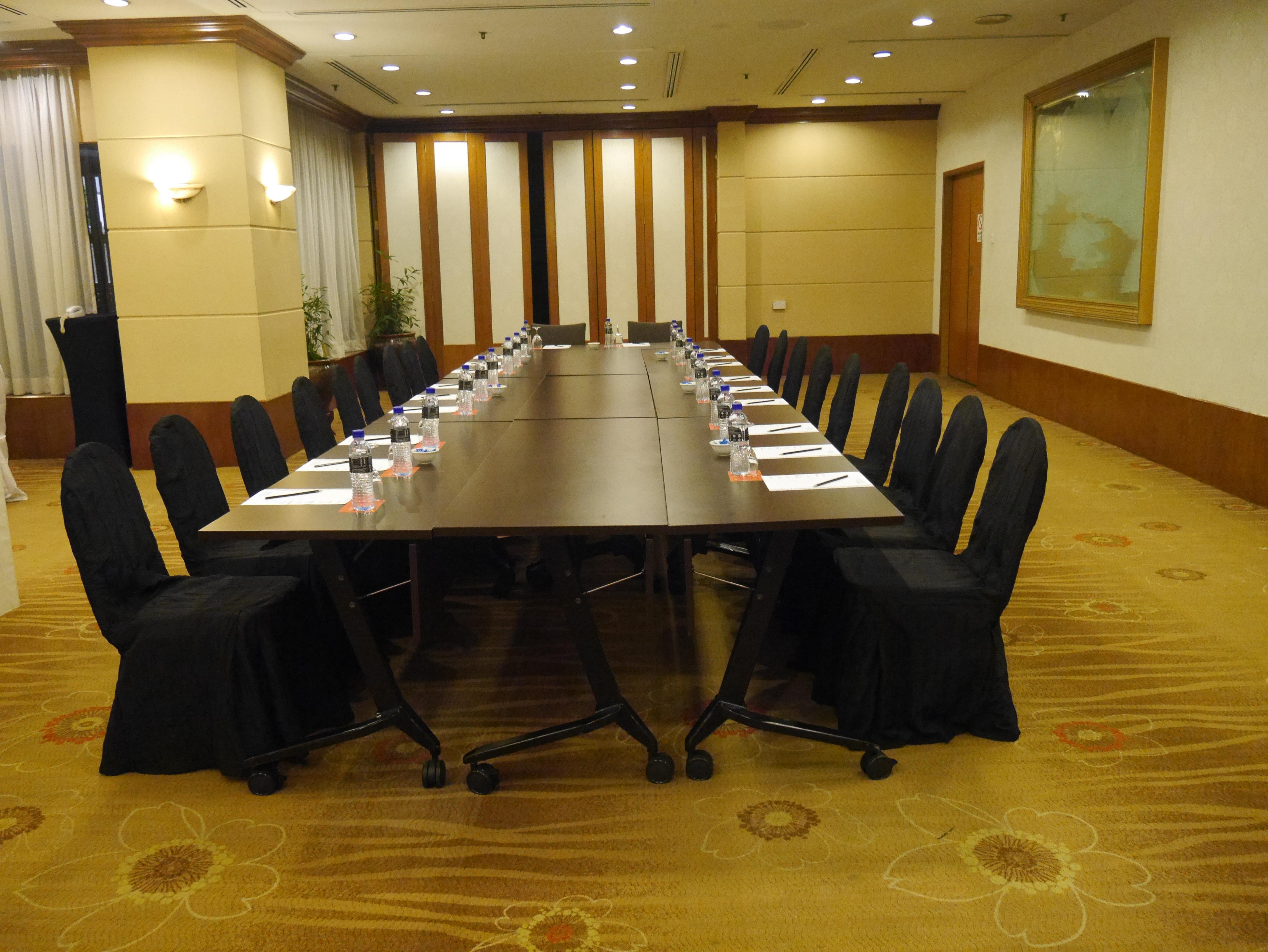 Seri Pacific Hotel Куала-Лумпур Экстерьер фото The photo shows a conference room setup featuring a long rectangular table surrounded by black upholstered chairs. The table appears to be organized for a meeting, with what looks like nameplates or notepads placed at each chair. The room has a forma