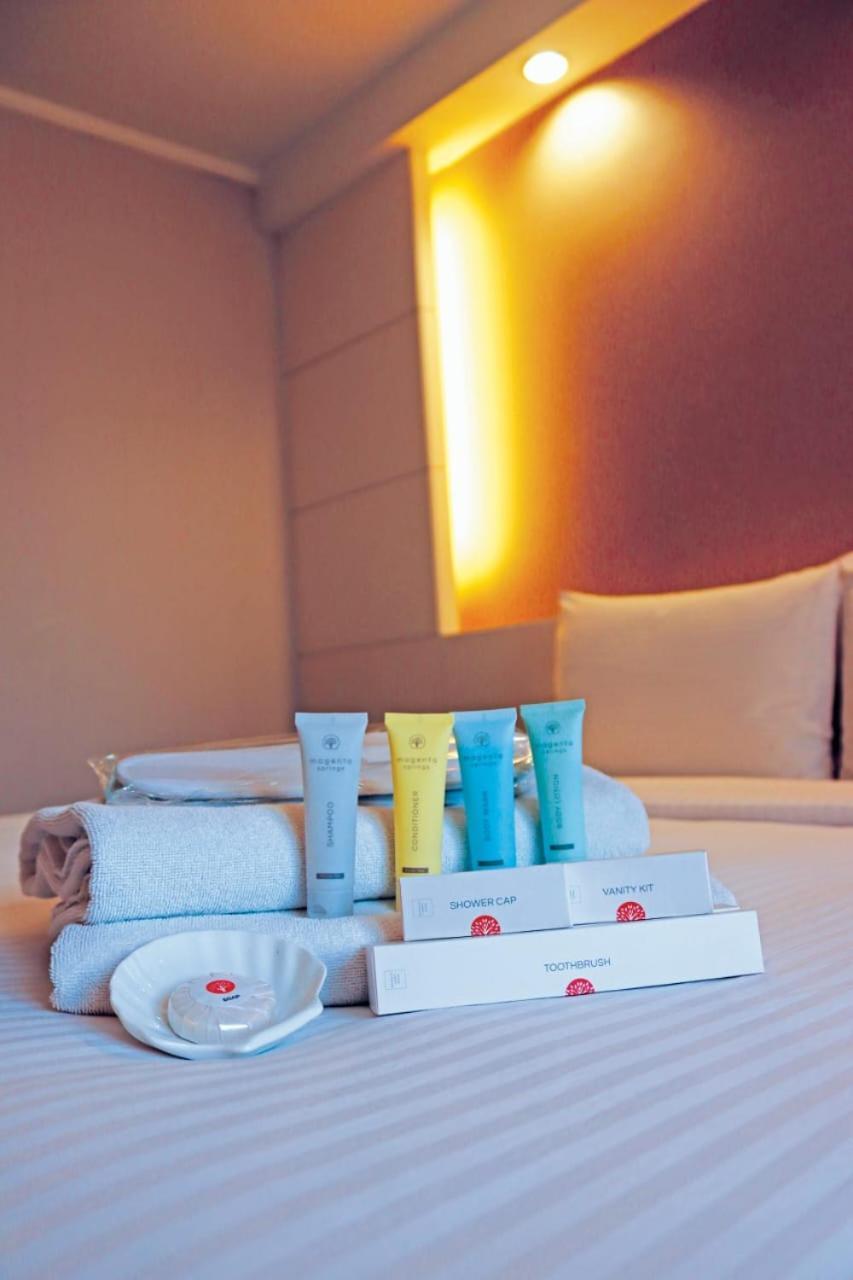Seri Pacific Hotel Куала-Лумпур Экстерьер фото The photo shows a neatly arranged setup on a bed, featuring several items typical of hotel amenities. There are folded white towels stacked on the bed, along with various small tubes of toiletries in different colors (blue, yellow, and green). Additi
