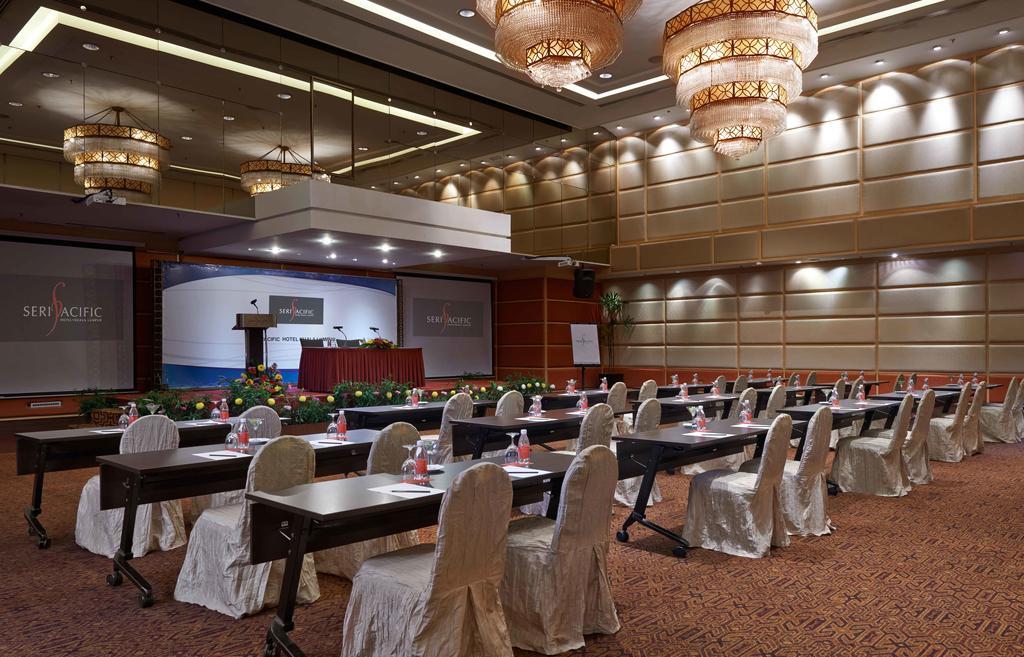 Seri Pacific Hotel Куала-Лумпур Экстерьер фото The photo shows the interior of a conference or meeting room. It features several rows of tables arranged in a classroom or theater style, each accompanied by chairs. The tables are covered with white cloths, and there are materials or small items pl