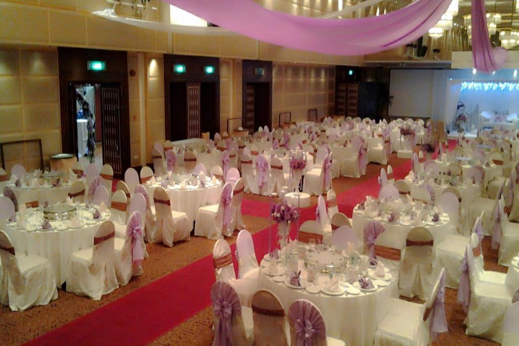 Seri Pacific Hotel Куала-Лумпур Экстерьер фото The photo shows a large banquet or event hall set up for a formal occasion, such as a wedding or reception. The space features multiple round tables covered in white cloths, each adorned with elegant tableware and centerpieces. The chairs are draped 